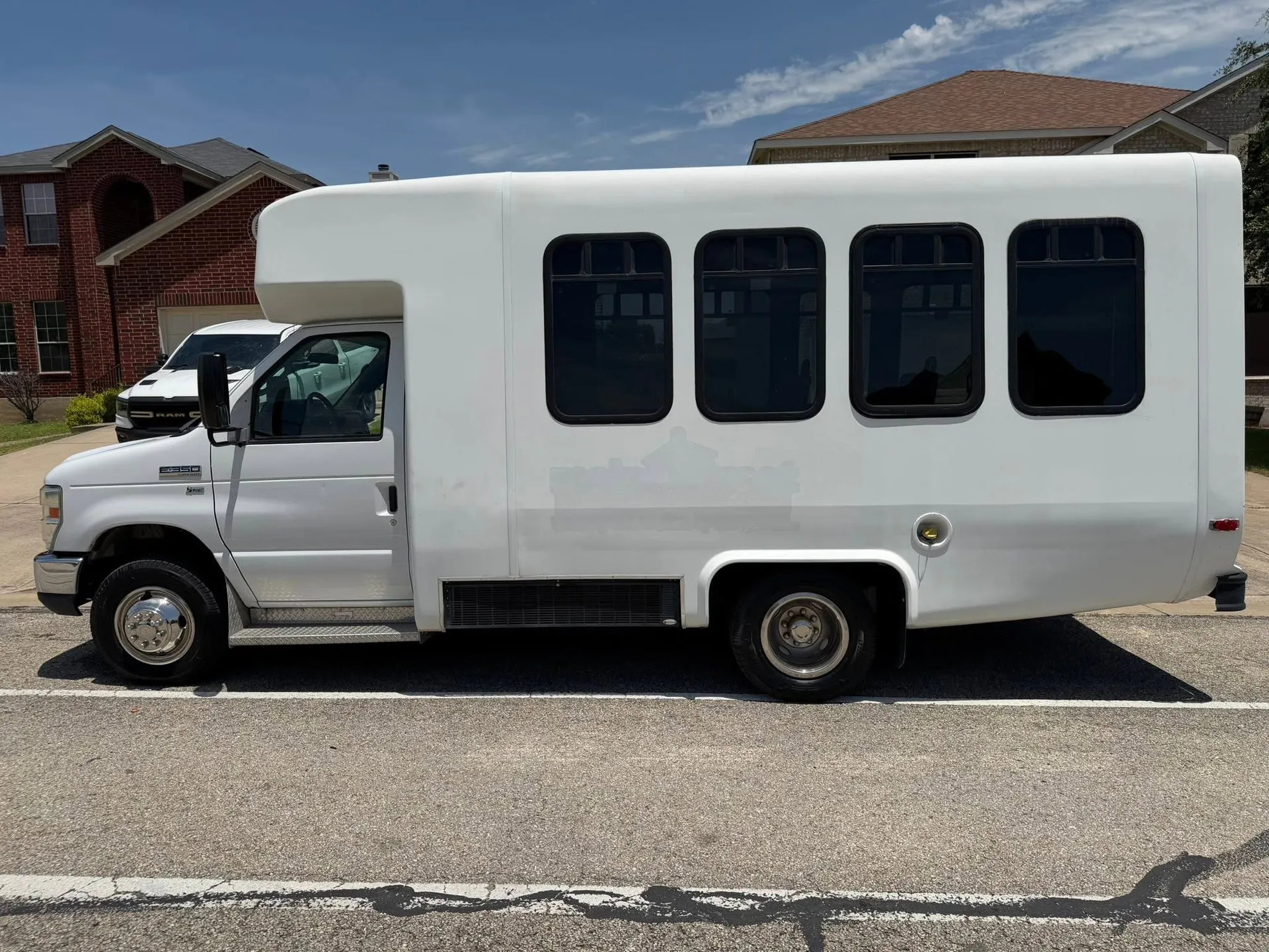 Real 2013 Ford E-350 14-passenger minibus in side profile on a sunny residential street